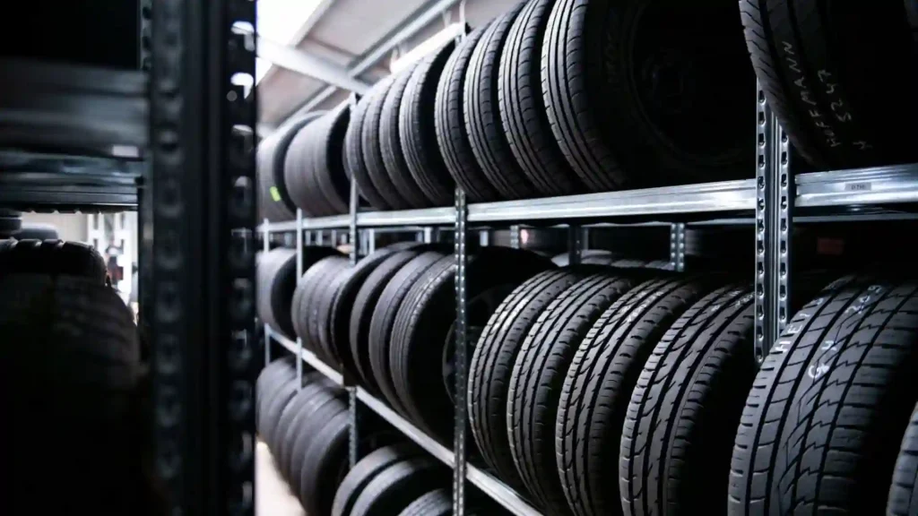 Blick in den Gang von einem Reifenregal. Darin sind auf 3 Ebenen immer 4 zusammengehörende Reifen nebeneinander auf dem Profil stehend gelagert.